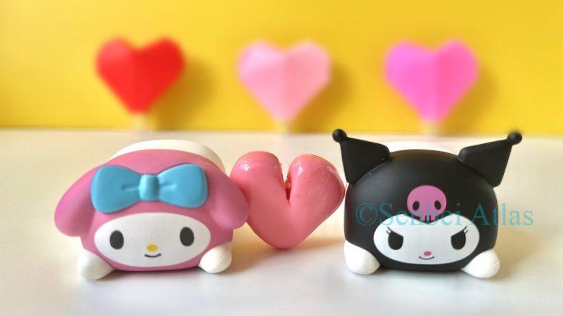 My Melody (マイメロディ) and Kuromi (クロミ) side-by-side with a heart between them, representing the popular Japanese tradition of 'Tomo' chocolate (友チョコ) shared among friends.