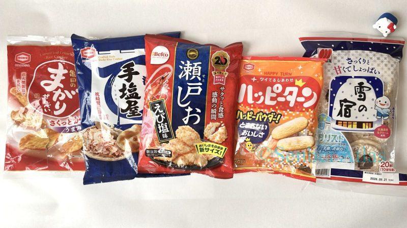 Five different senbei packages (Magari Senbei, Teshioya, Seto Shio, Happy Turn, and Yuki no Yado) lined up with a Hello Kitty figure.