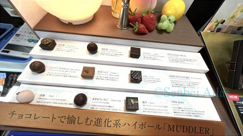 An exhibition of MUDDLER (マドラー) chocolates. Since the chocolates are themed around highballs, they are lined with bar-themed, subdued lighting, cocktail glasses, and imitation fruit.