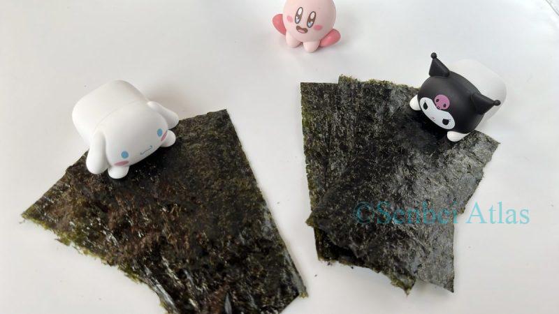Cinnamoroll and Kuromi each holding onto nori seaweed, representing the global competition for nori, while Kirby watches them from the background.