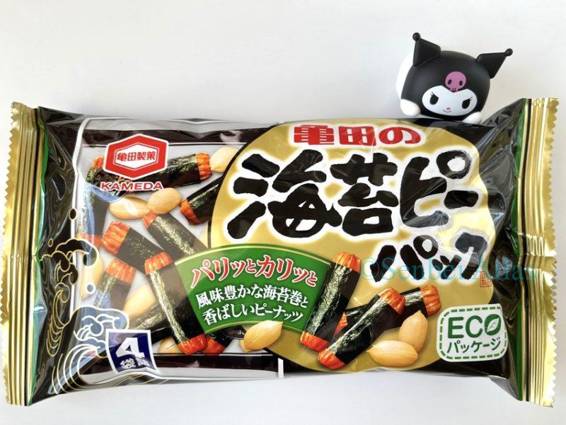 A product package of Kameda Seika (亀田製菓) "Nori-p Pack" (海苔ピーパック) with a small Kuromi (クロミ) character figure standing next to it and touching the corner of the bag.