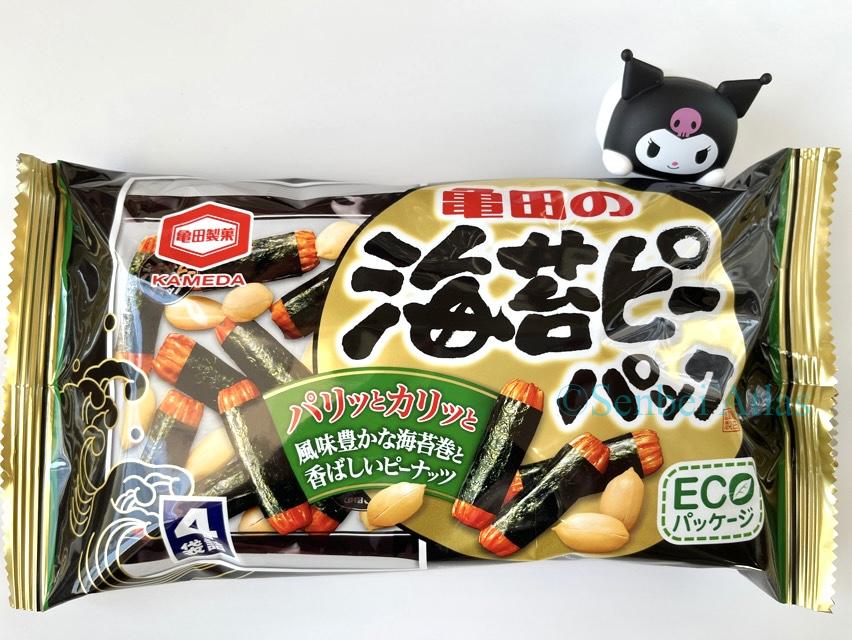 A product package of Kameda Seika (亀田製菓) "Nori-p Pack" (海苔ピーパック) with a small Kuromi (クロミ) character figure standing next to it and touching the corner of the bag.