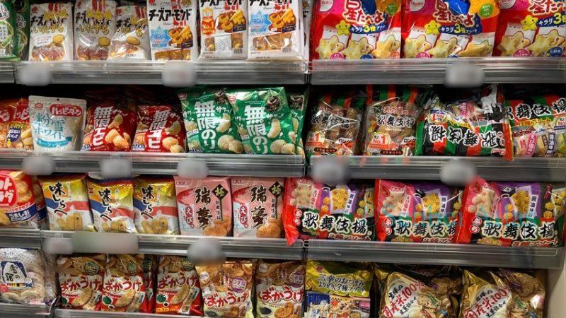 A wide selection of over ten types of Japanese rice crackers on a supermarket shelf, but notably missing any seaweed-wrapped Norimaki Senbei.