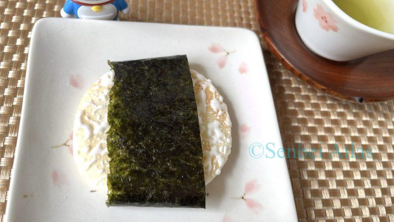 Yuki no Yado (Japanese rice cracker), a sweet milk-glazed senbei, tried with a savory nori wrap. A Doraemon figure and teacup provide a consistent Japanese theme.