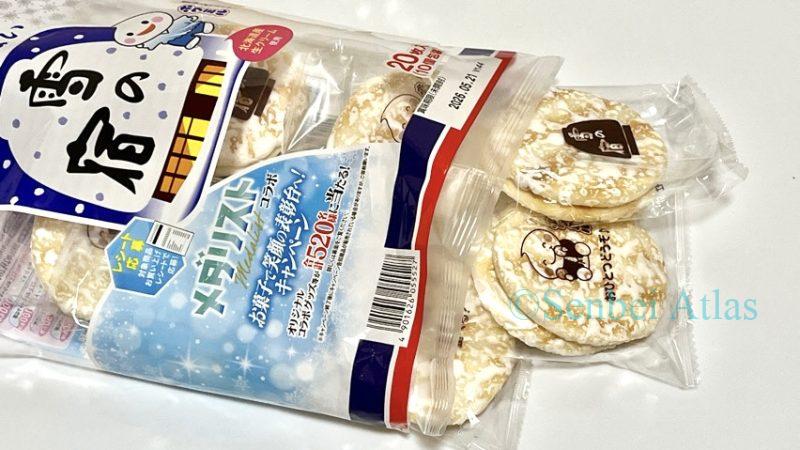 Individual packaging of Yuki no Yado (雪の宿) coming out of the main bag: Japanese rice crackers (Senbei) with white sugar frosting.