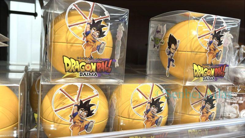 A product containing chocolate crunch in a Dragon Ball -shaped tin case (ドラゴンボールDAIMAチョコクランチ缶). These are from the latest series, "Dragon Ball DAIMA",so Goku (悟空) and Vegeta (ベジータ) look so adorable in their "mini" or child forms on the packaging. 
