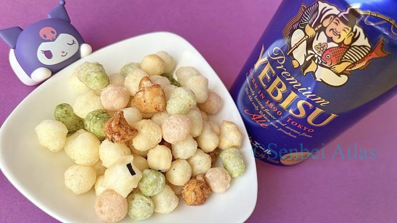 Hina Arare (ひなあられ) snacks on a plate with Yebisu Beer (ヱビスビール) and Kuromi (クロミ) in the background.