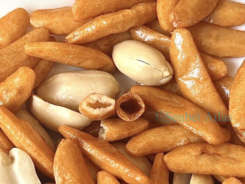 A close-up Cross-section of a Kaki-no-Tane (柿の種) rice cracker showing the thin dough and Hollow interior.