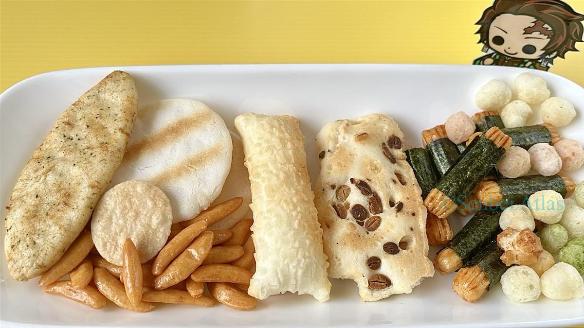 An assortment of Senbei (せんべい), Okaki (おかき), and Arare (あられ) with a Tanjiro Kamado (竈門炭治郎) sticker in the background.