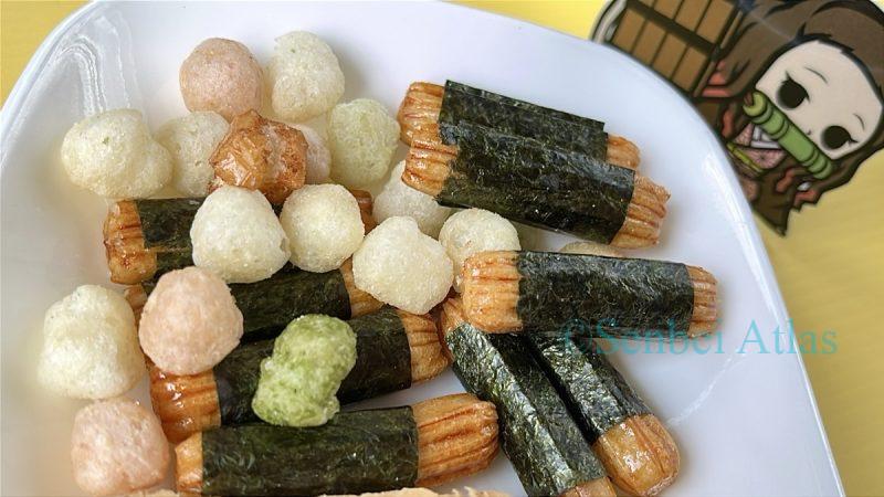 Two varieties of Arare (あられ) rice crackers on a plate with a Nezuko Kamado (竈門禰豆子) sticker behind them.