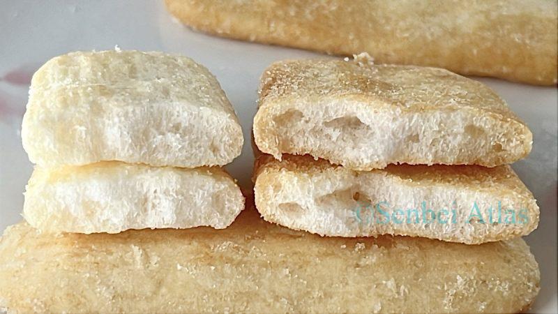 A close-up cross-section (断面) comparison of Happy Turn (ハッピーターン) and Ajishirabe (味しらべ), showing the difference in their inner texture and airiness.