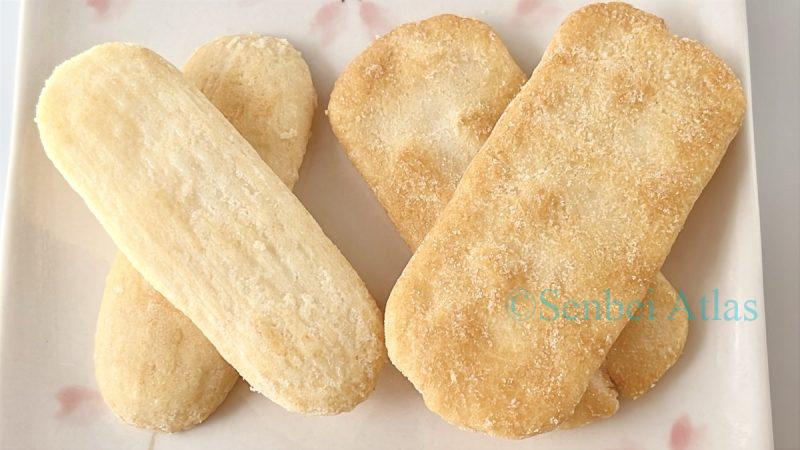 Two pieces each of Happy Turn (ハッピーターン) and Ajishirabe (味しらべ) arranged on a plate for comparison.