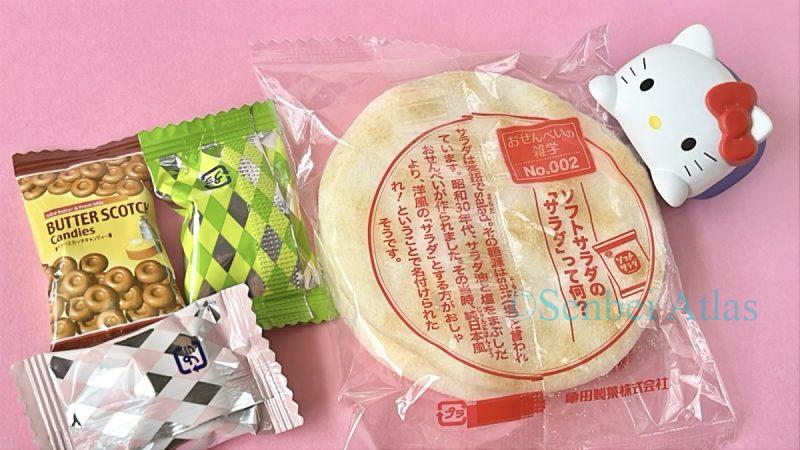 Various candy wrappers and a Soft Salad (ソフトサラダ) wrapper with a Hello Kitty (ハローキティ) figure beside them.