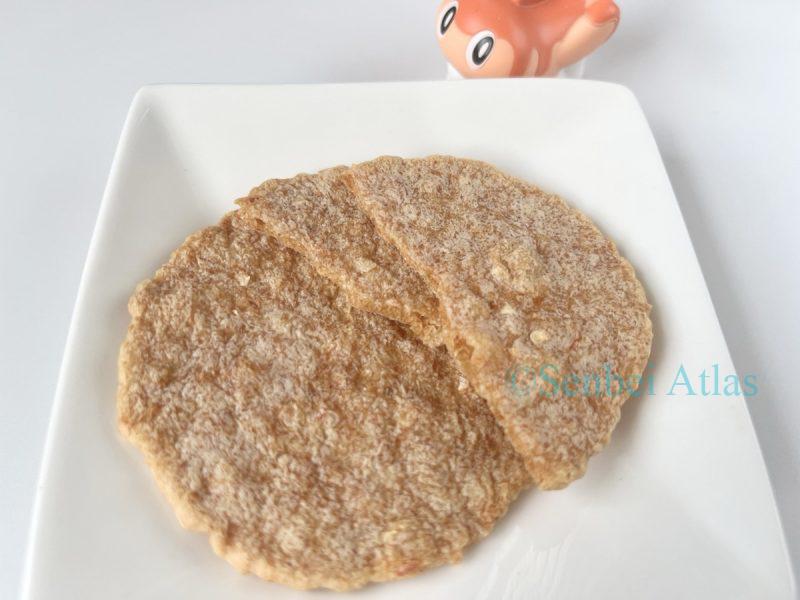 Yukari (ゆかり) shrimp cracker on a plate with a cross-section and Tatsugiri (シャリタツ) in the background.